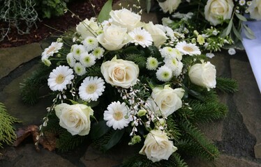 Weiße Blumen im Trauerkranz auf dem Friedhof