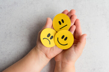 kids emotional intelligence. Little kid holding happy sad and unsatisfied yellow faces. 