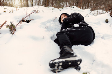 Fototapeta na wymiar Caucasian man feeling cold discomfort covering his mouth and face from the wind, lying down at extreme snow elements environment on a snowy mountain with low temperature. Sick man with hypothermia.