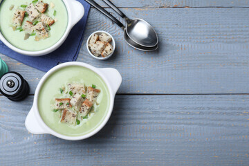 Delicious asparagus soup with croutons served on grey wooden table, flat lay. Space for text