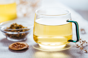 Cup of chamomile tea in transparent mug served with slice of lemon and orange. Tea break. 