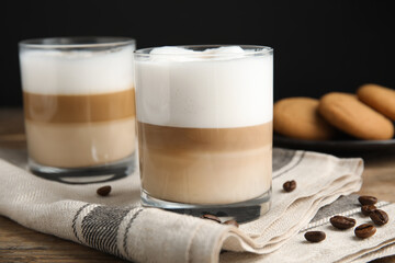 Delicious latte macchiato and coffee beans on wooden table