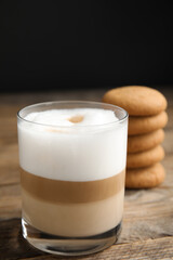 Delicious latte macchiato and cookies on wooden table