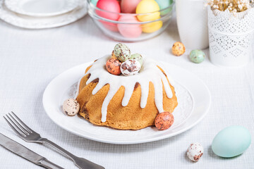 Easter cake with colorful eggs in a chocolate nest on pink background and flowers. Happy Easter concept. Dessert also known as  Kuglof. Top view