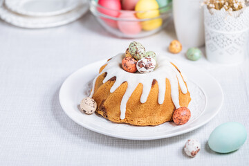 Easter cake with colorful eggs in a chocolate nest on pink background and flowers. Happy Easter concept. Dessert also known as  Kuglof. Top view