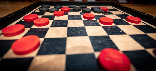 Perspective of red and black checkers  game pieces on a board