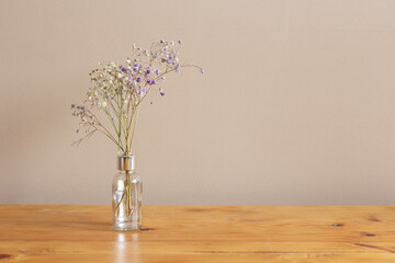 Fototapeta na wymiar Fragile flowers in vase on wooden table