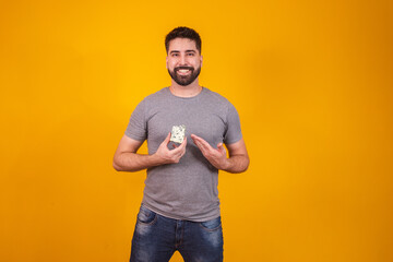 Handsome man tasting a piece of gorgonzola cheese on yellow background