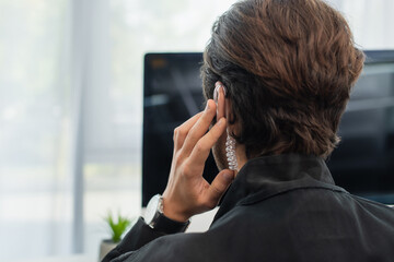 back view of security man touching earphone while working in office.