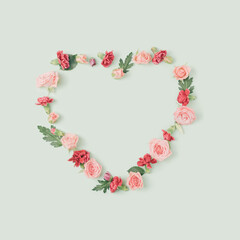 Spring flowers arranged in a shape of a heart on a pastel green background. Love and romace concept