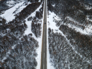 High angle top down aerial view drone image on road trough the trees and forest in mountain range covered with white snow in winter day near Knjazevac in Serbia car Travel journey and vacation concept