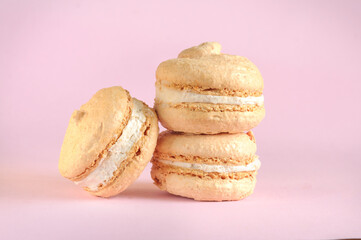 Light beige macaroon cookies on a pink background with selective focus and copy space