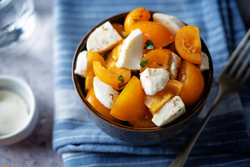 Yellow tomatoes basil pepper mozarella salad in a bowl