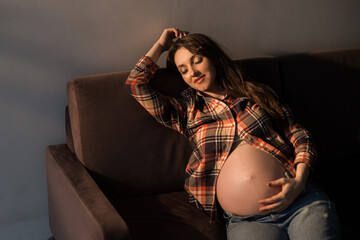 Young pregnant woman sitting on the sofa. Pregnant woman at home