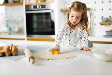 Cute little girl having fun while making a cake in the kitchen
