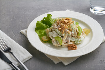 classic american waldorf salad made of apples celery walnuts grapes mayonnaise whipped cream white plate grey background