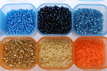 Plastic organizers with different beads on white background, top view