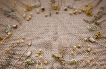 Background from natural materials. Frame made of dried flowers on burlap close-up. Flat lay, top view, copy space, eco concept.