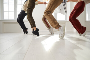 Youth dances. Group of hip hop dancers who together perform stand on toes during rehearsal in dance studio. Low section of legs of young people in casual clothes who simultaneously stand on their toes - obrazy, fototapety, plakaty