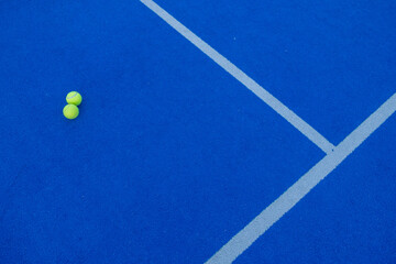 two balls on the line of a blue synthetic grass paddle tennis court