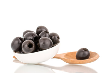 A few pickled black olives in a white saucer with a wooden spoon, macro, isolated on white.