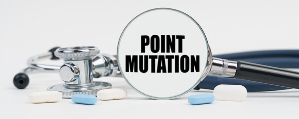On a white surface are pills, a stethoscope and a magnifying glass inside which is written - Point mutation