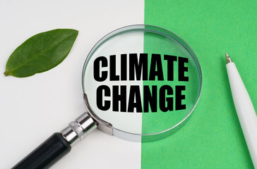 On a white-green background, a pen, a piece of paper and a magnifying glass with the inscription - Climate Change