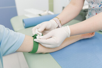 Taking a blood test from a vein in the treatment room. Nurse pricking a syringe with a needle into...