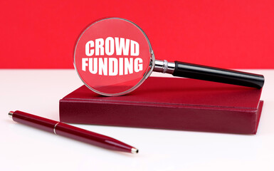 On a white and red background, a notebook, a pen and a magnifying glass, inside which the inscription - CROWD FUNDING