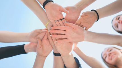 Cheerful girls join hands together as a sign of unity and joint successful work. Teamwork stacking hand concept.
