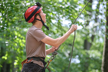 Man belays his partner climber with belaying device and rope. Climber's handsman holding equipment...
