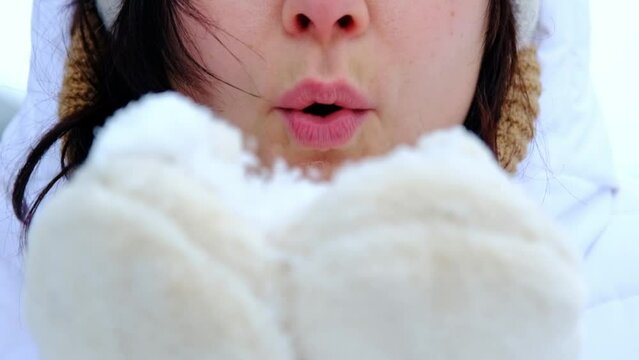 A woman blows red sequins in the shape of hearts from warm fur mittens. Slow-motion video, close-up. Valentine's Day, love, feelings
