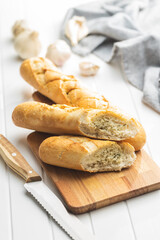 Roasted baguette with garlic butter. Crunchy sliced garlic bread on white table.