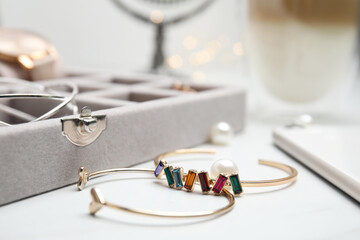 Beautiful bracelets and jewelry box on white table, closeup - obrazy, fototapety, plakaty