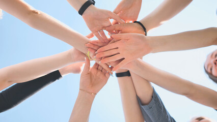 Cheerful girls join hands together as a sign of unity and joint successful work. Teamwork stacking hand concept.