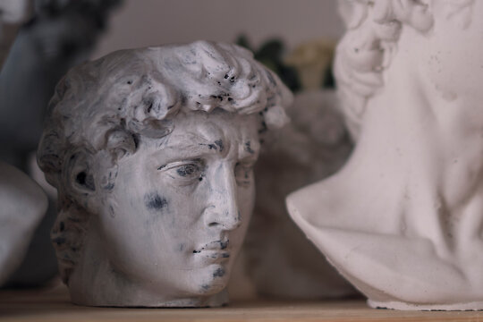 group of busts of David stand on a shelf. sculptor's workspace. antique plaster busts