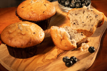 Home nade muffins with blueberries on wooden chopping board.