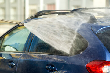 Closeup of male driver washing his car with contactless high pressure water jet in self service car...