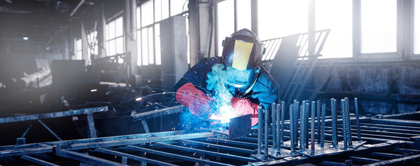 Banner factory worker industrial welder in protective uniform on workplace