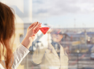 A laboratory assistant girl looks at the color of the solution in a chemical laboratory