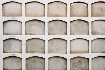 Wall of a cemetery with the holes of the niches one on top of the other covered.