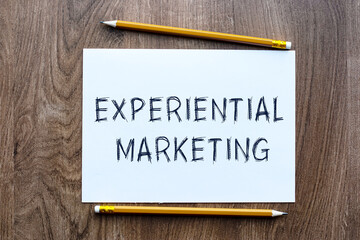 The text EXPERIMENTAL MARKETING is written in a notebook which lies on a wooden table. Lettering on a business or financial theme. Business concept.