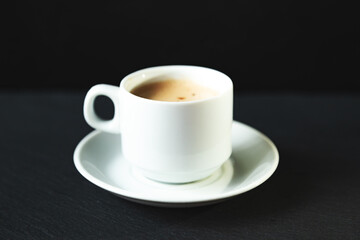 White cup of espresso coffee on a black background.