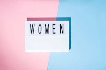 Women text on the lightbox. Concept of feminism on a blue and pink background. Top view