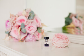 perfume bottle on background of Tender Bride's bouquet with delicate pink tea roses. Wedding day. Morning preparation of the Bride