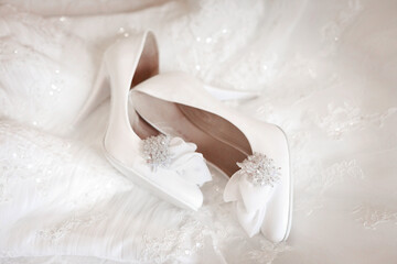 Bride's wedding shoes on a wedding dress. Bride's morning. Wedding accessories in white colors. Preparation to wedding day. Elegant female footwear