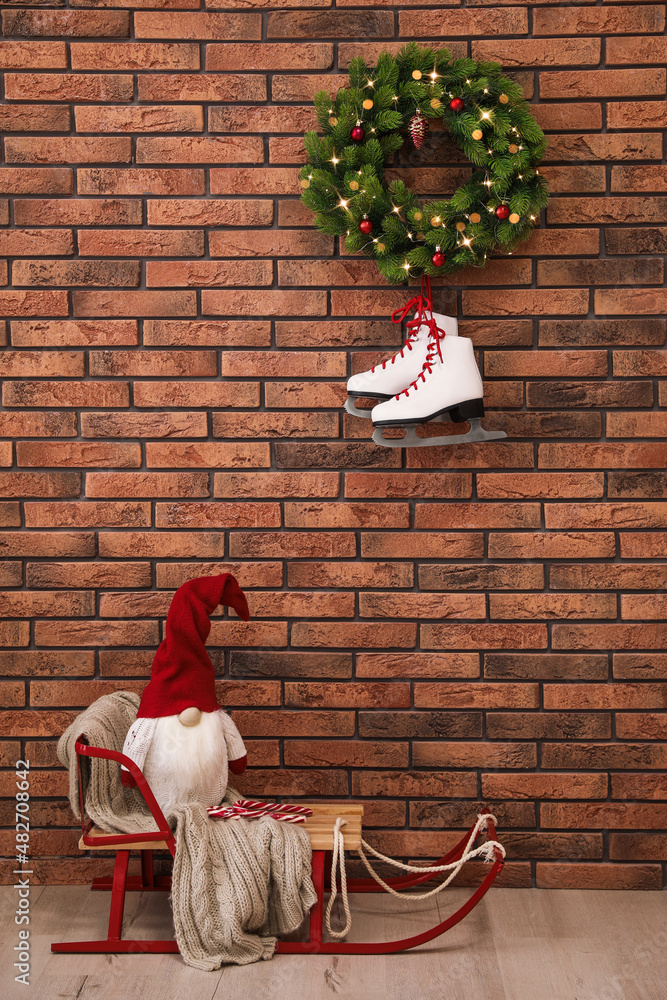 Sticker Christmas gnome on sleigh near brick wall with pair of ice skates and festive wreath indoors