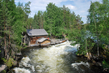 Old mill hut along a river stream and between dense green forest