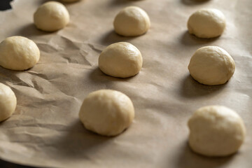 Hamburger buns with sesame seeds prepared for baking. Baking sheet with blanks. Clouse-up
