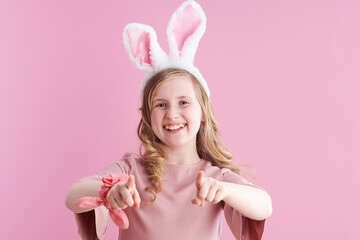 Obraz na płótnie Canvas Portrait of happy child in dress pointing in camera on pink